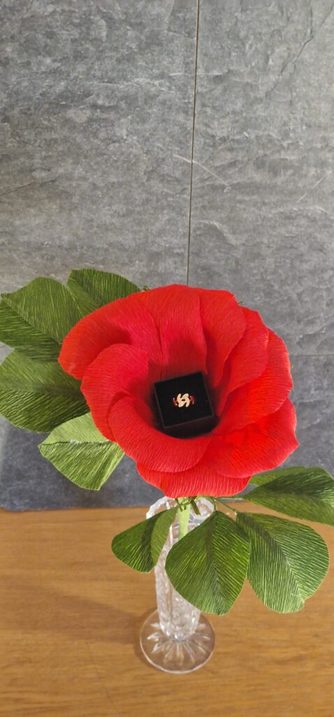 Handcrafted crepe paper rose with realistic green leaves
