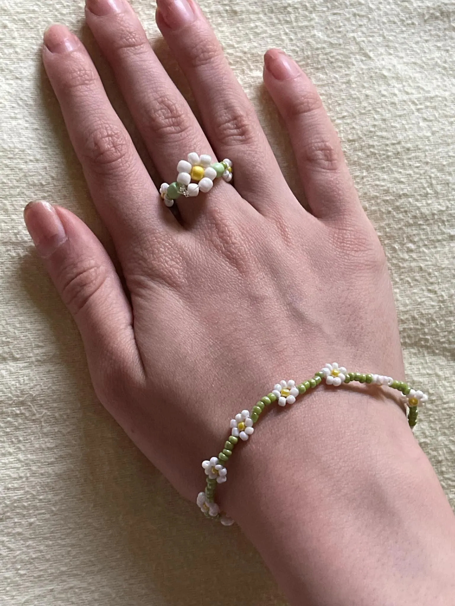 Handmade daisy beaded bracelet worn on wrist in white and green floral design